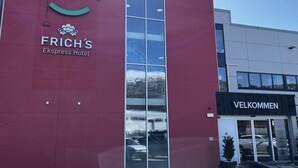 En byggnad med en röd fasad, där logotypen ”ALTI” och skylten ”FRICH’S Ekspress Hotel” syns.