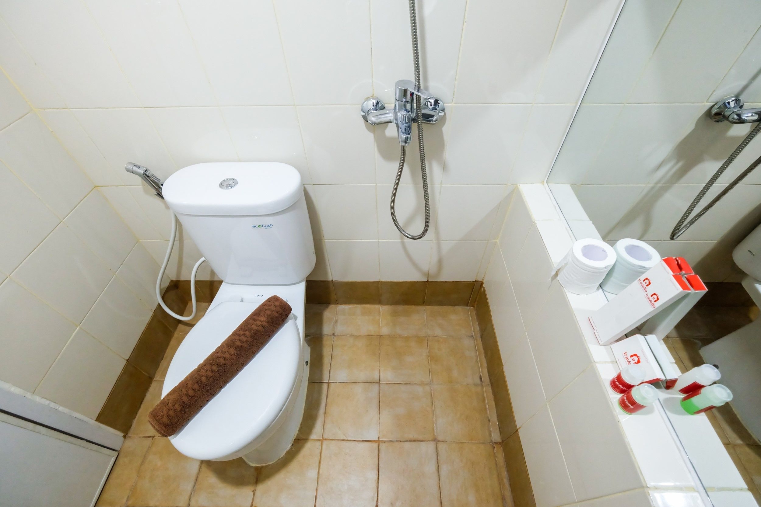 A bathroom with a toilet, shower, and a sink with toiletries.
