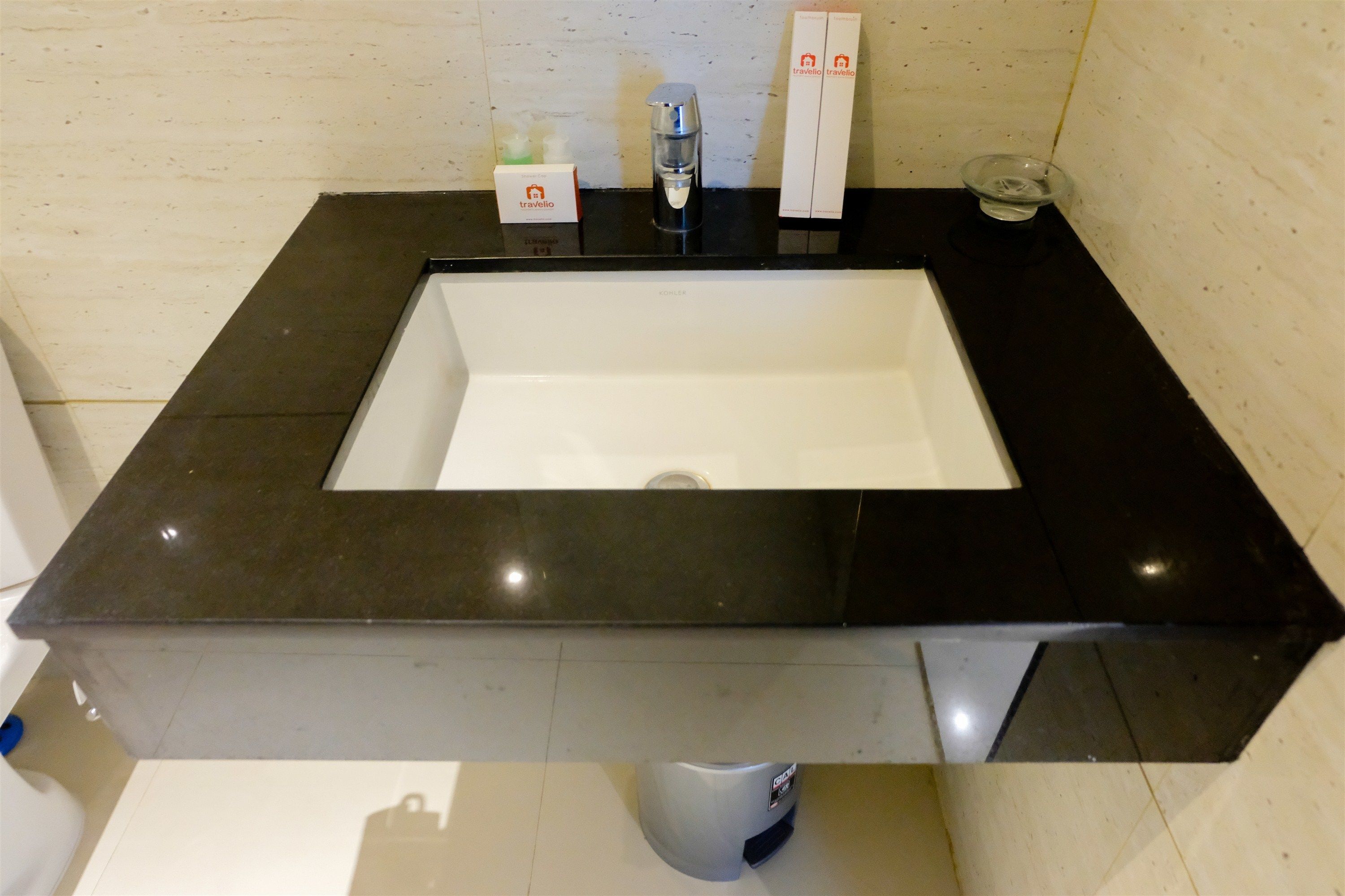 Casa de banho moderna com bancada preta, lavatório branco e dispensador de sabonete.