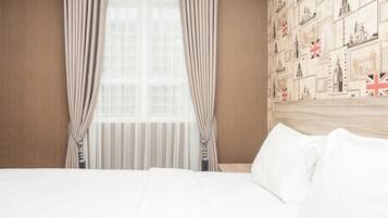 Habitación de hotel con una cama grande, cortinas, una ventana con persianas y una pared decorada con sellos postales.