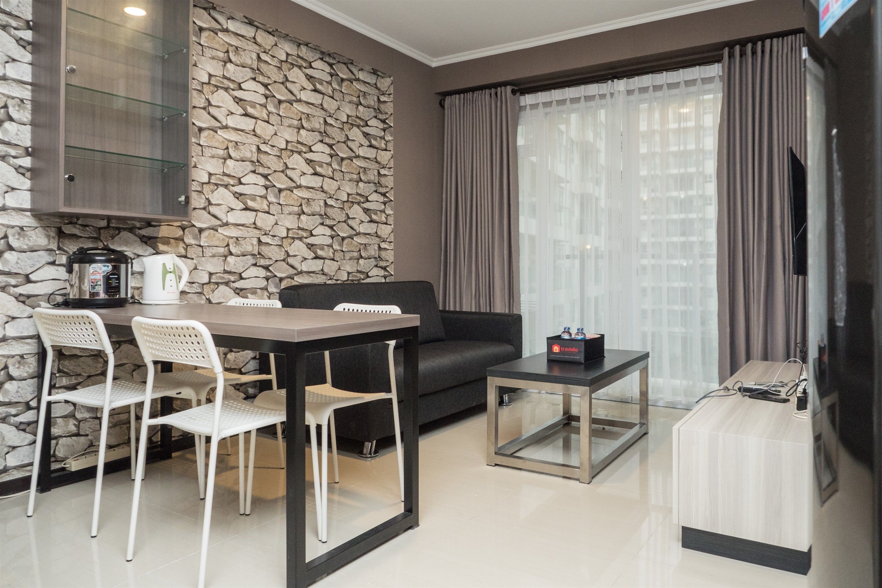 Una sala moderna con pared de piedra, un sofá, una mesa de centro y un comedor con sillas.