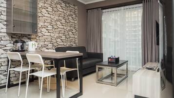 Una sala moderna con pared de piedra, un sofá, una mesa de centro y un comedor con sillas.