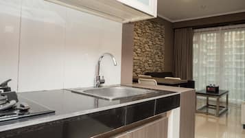 A modern kitchen with a black countertop, stainless steel sink, and a stone accent wall.