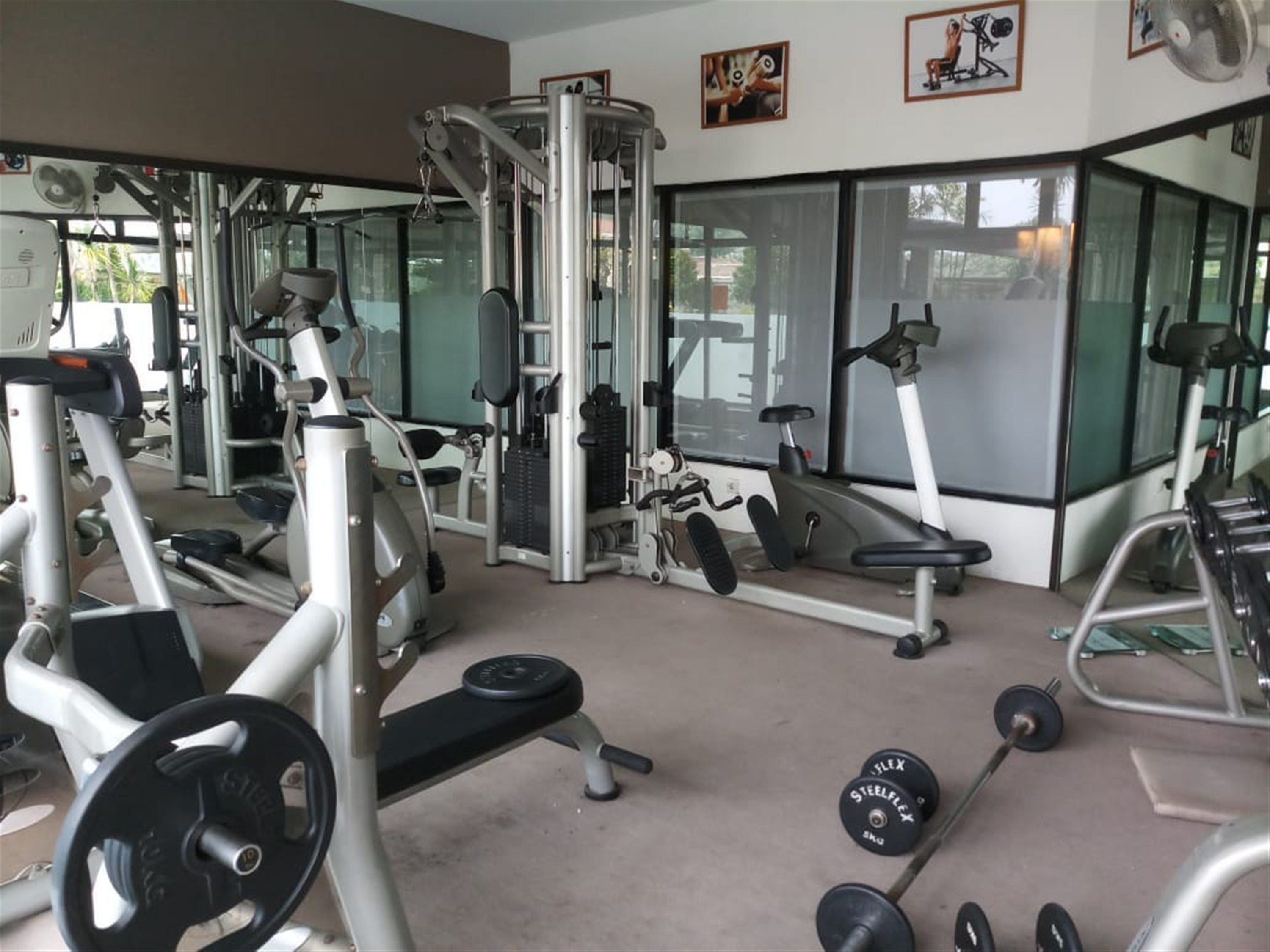Un gimnasio con equipo de ejercicio variado, incluyendo máquinas de pesas, un banco y mancuernas.