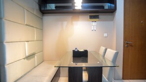A modern room with a glass-top table, cushioned seating, and a wooden door. - Great Location 2BR Maple Park Apartment (Jakarta)
