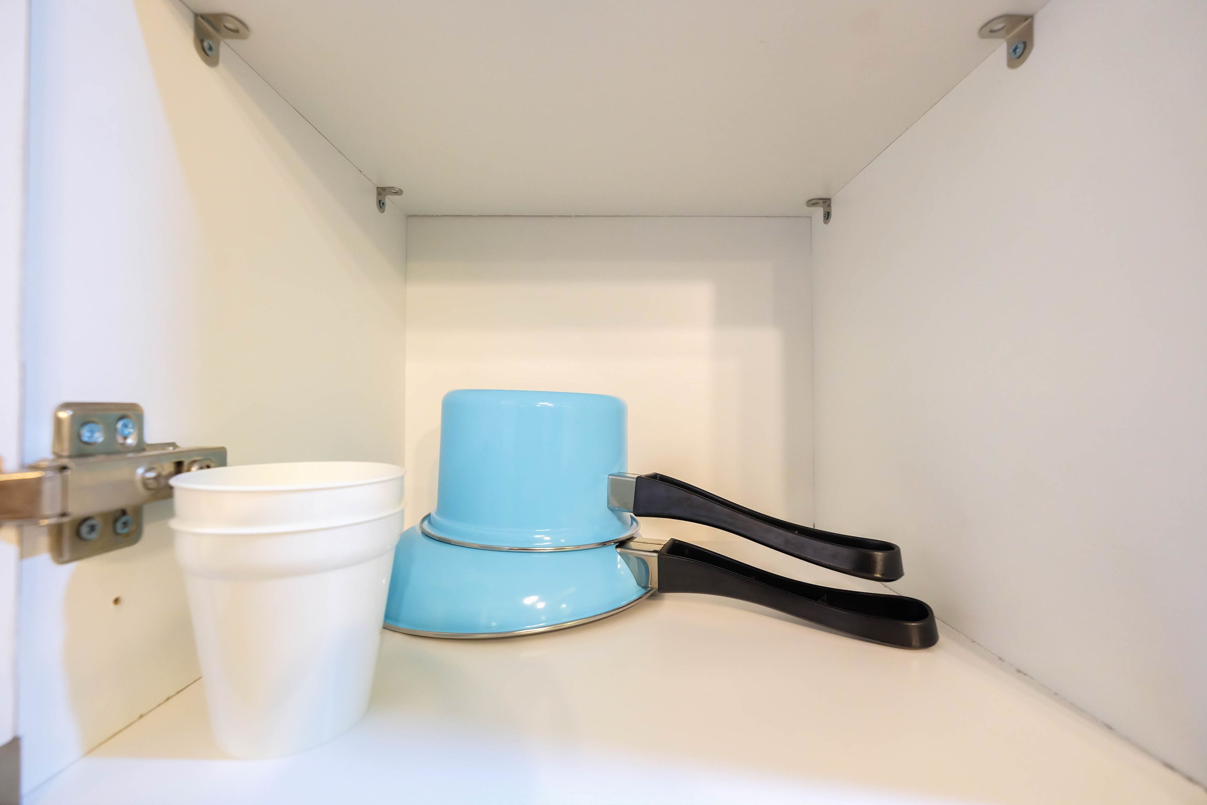 Une petite salle de bain avec des toilettes blanches, une poubelle bleue et un robinet noir.
