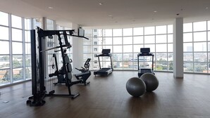 A spacious gym with large windows, exercise equipment, and a city view. - Fabulous Tree Park City Studio Apartment near ICE BSD (Tangerang)
