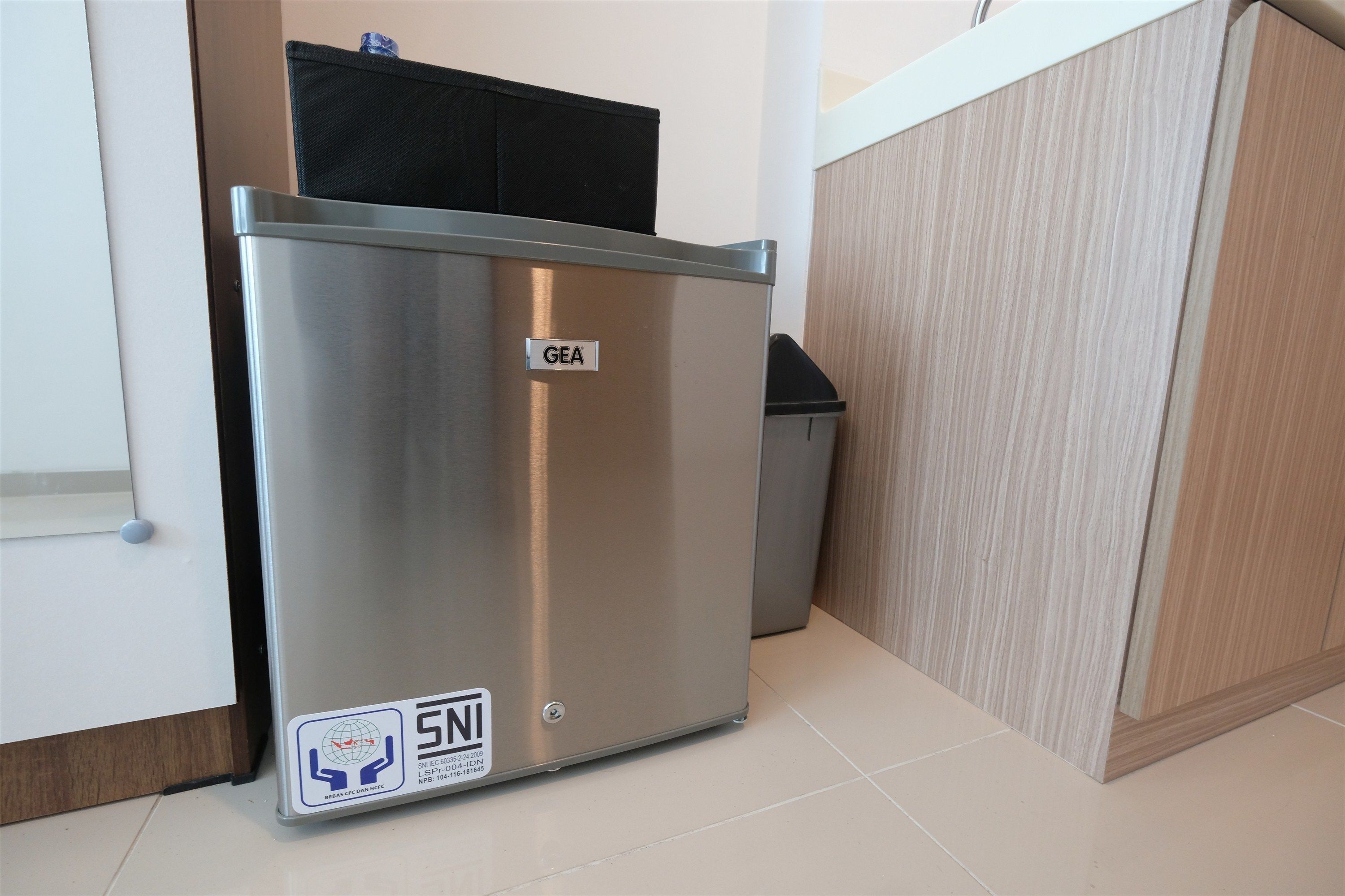 A GEA refrigerator in a kitchen with a tiled floor and wooden cabinets.