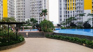 A residential building with multiple floors, a swimming pool, and a covered walkway. - Furnished Studio Apartment @ The Springlake Summarecon (Bekasi)