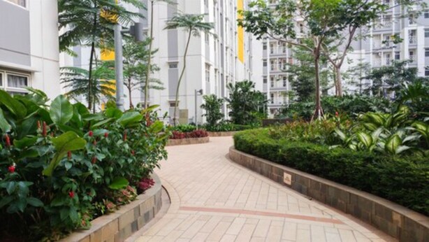 A pathway flanked by lush greenery and modern buildings. - Furnished Studio Apartment @ The Springlake Summarecon (Bekasi)