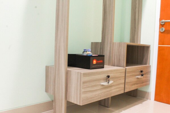 A bathroom with a wooden vanity, a mirror, and a small shelf with toiletries.
