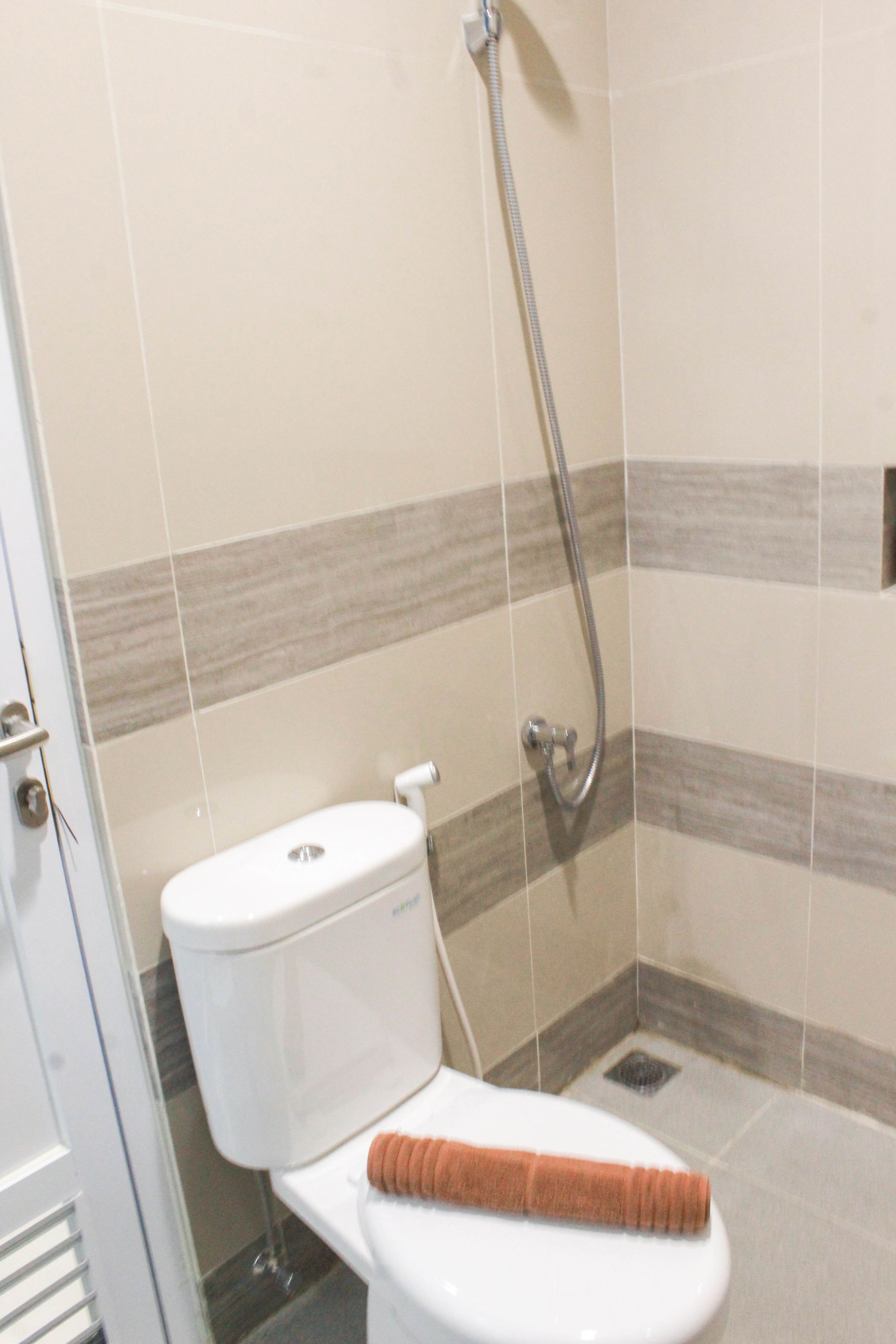 Une salle de bain avec des toilettes, une douche et une serviette posée sur le siège.