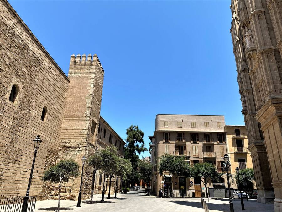 A street with historic buildings, including a prominent tower and a building with a balcony.