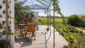 Una terraza de madera con una pérgola, una mesa y sillas.