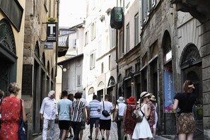 A narrow street with historic buildings, a sign for a lottery, and people walking. - Casa di Sofia Città Alta (Bergamo)