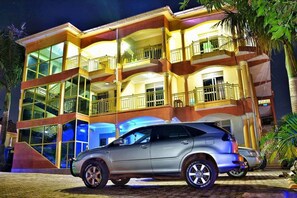 A multi-story building with balconies, large windows, and a parked car in front. - Royal Matt Hotel (Kampala)