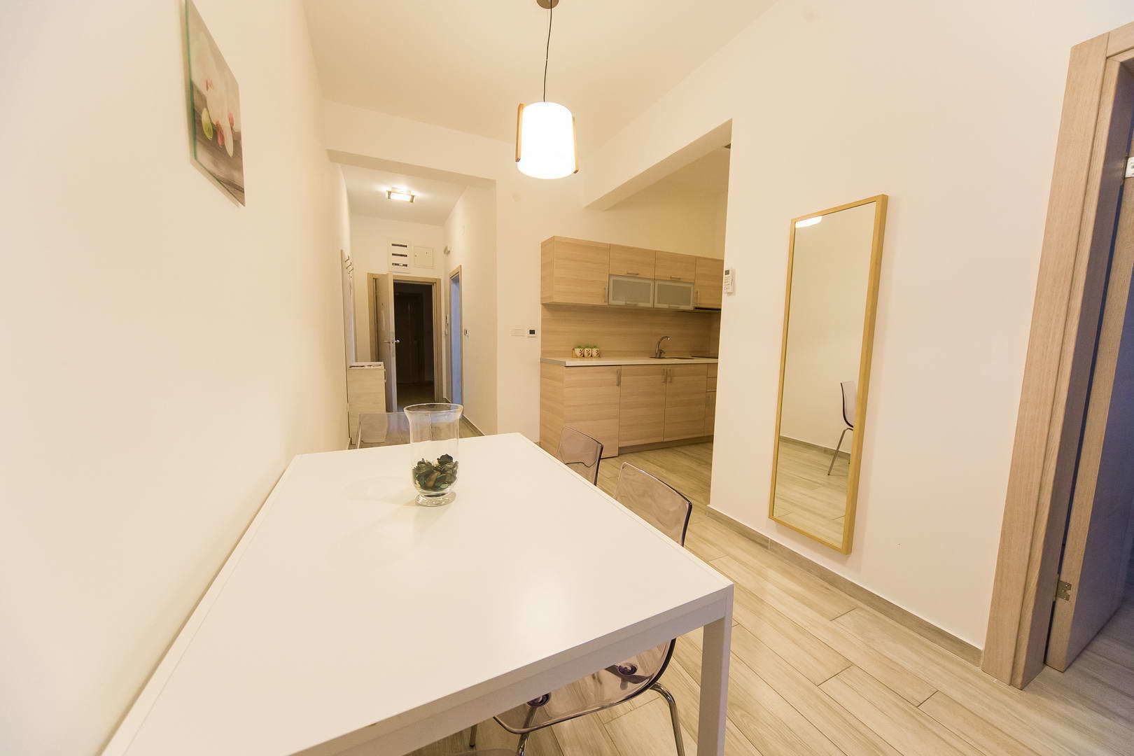 A modern kitchen with wooden cabinets, a white countertop, and a hanging light fixture.