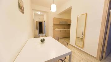 A modern kitchen with wooden cabinets, a white countertop, and a hanging light fixture.