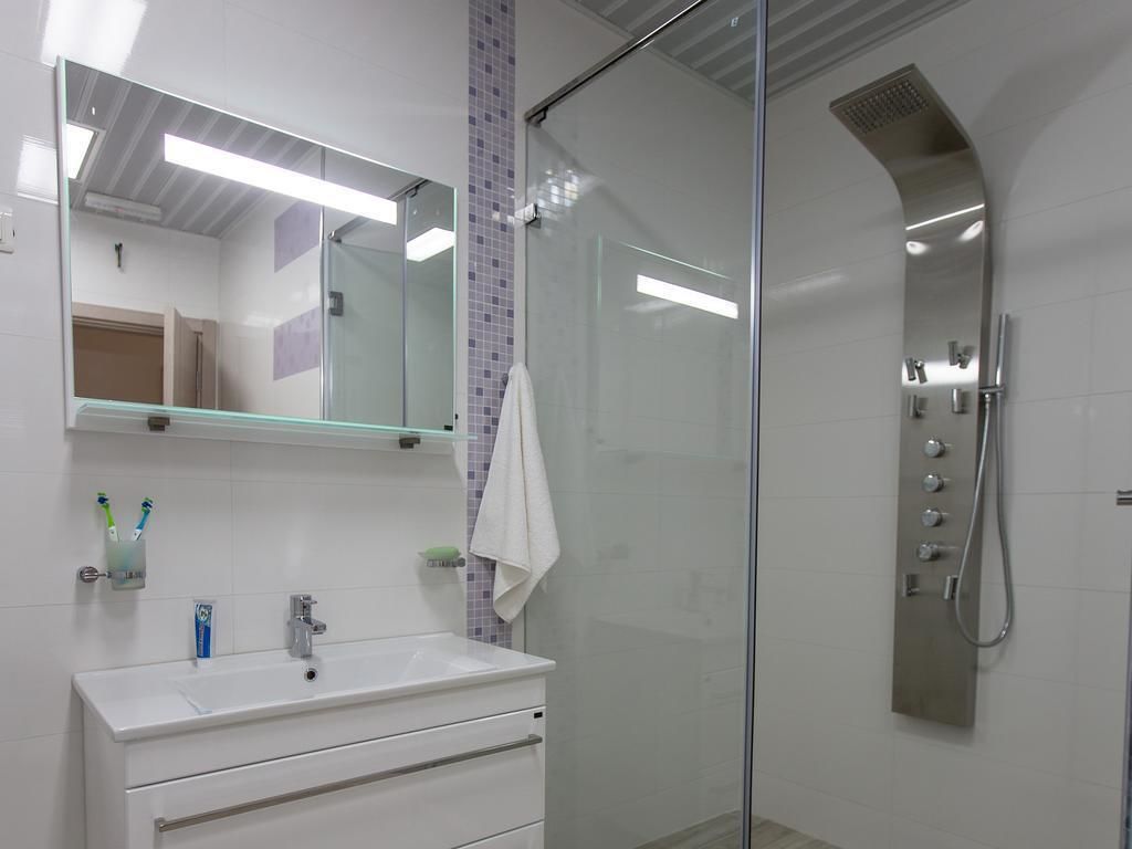 Une salle de bain avec une douche à parois de verre, un lavabo blanc et un miroir au-dessus.
