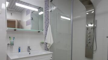 Une salle de bain avec une douche à parois de verre, un lavabo blanc et un miroir au-dessus.