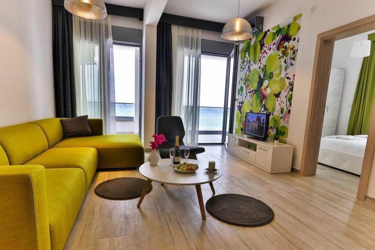 A modern living room with a yellow sofa, a round coffee table, and a television on a stand.