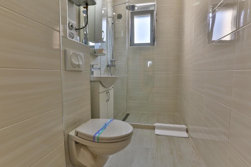Un baño con inodoro, lavamanos, espejo y ducha.