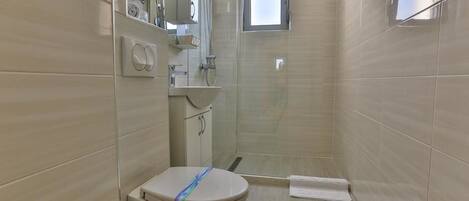 Un baño con inodoro, lavamanos, espejo y ducha.