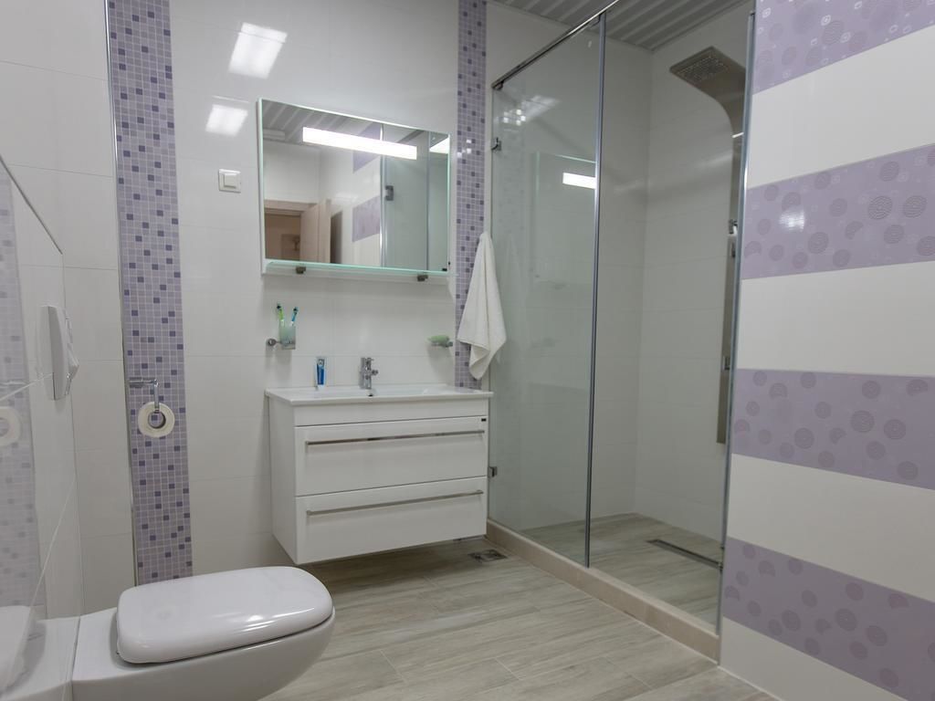 Un baño con inodoro, lavabo con espejo y cabina de ducha con mampara de vidrio.