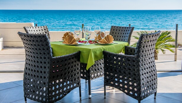 A table set for two with a green tablecloth, two chairs, and a view of the ocean. - Apart Hotel Sea Fort (Sutomore)