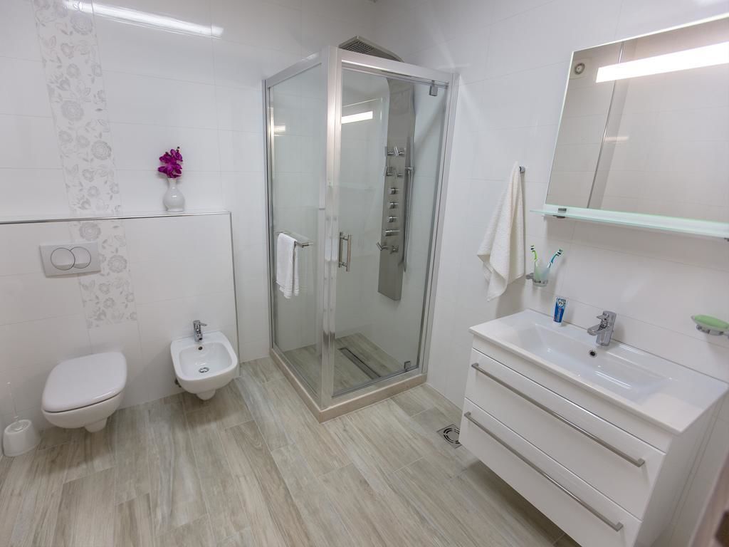 Un baño moderno con inodoro, bidé, cabina de ducha de vidrio y tocador con espejo.