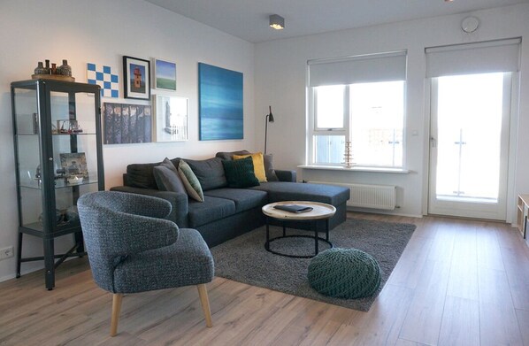 A modern living room with a sectional sofa, a round coffee table, and a glass cabinet.