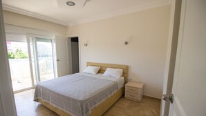 Un dormitorio con cama, mesita de noche, puerta y vista al exterior.