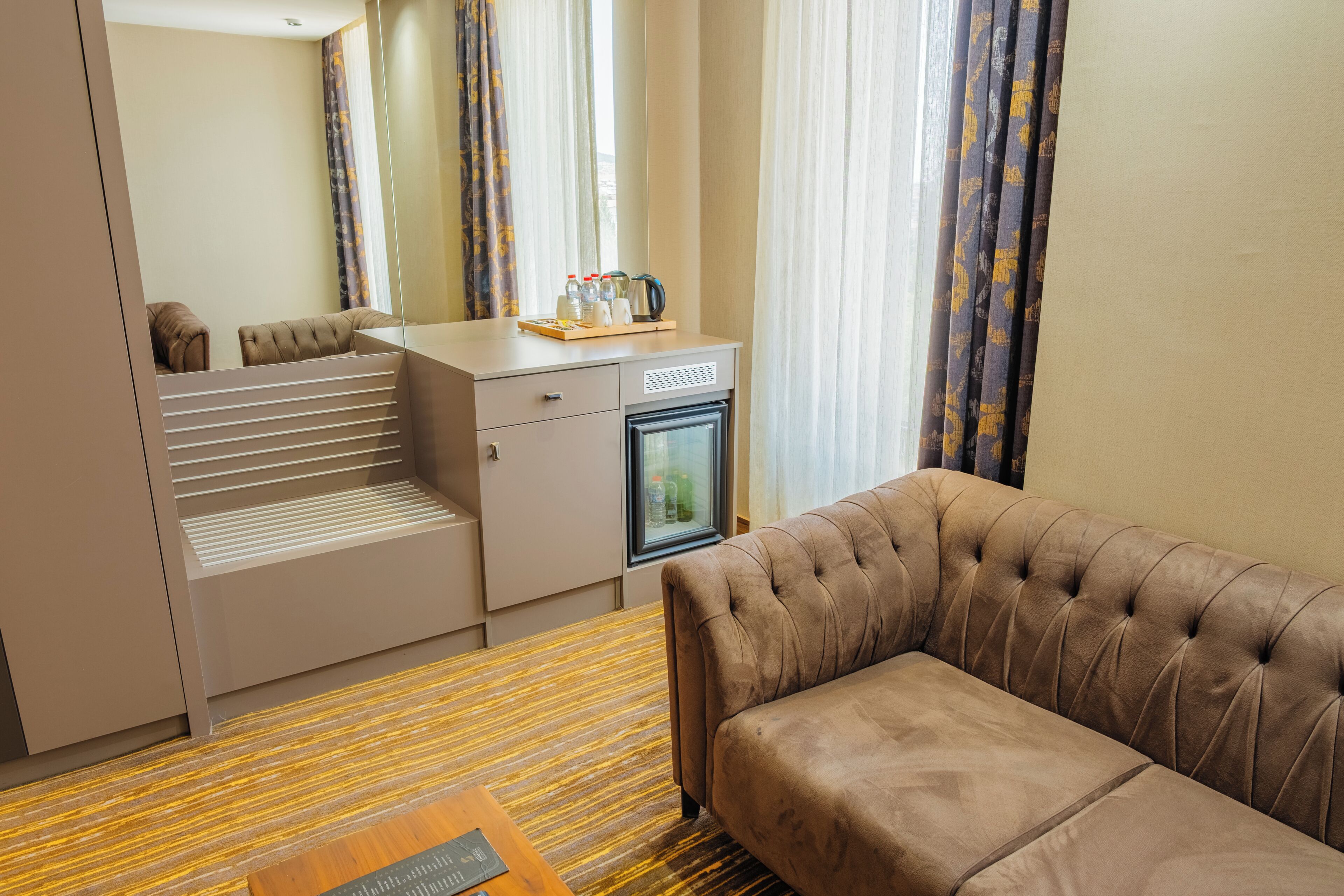 Habitación de hotel compacta con sofá, kitchenette y cama.