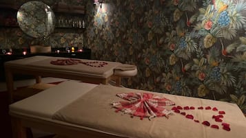 Relax in a serene space with a massage table, round mirror, and elegant arrangements.