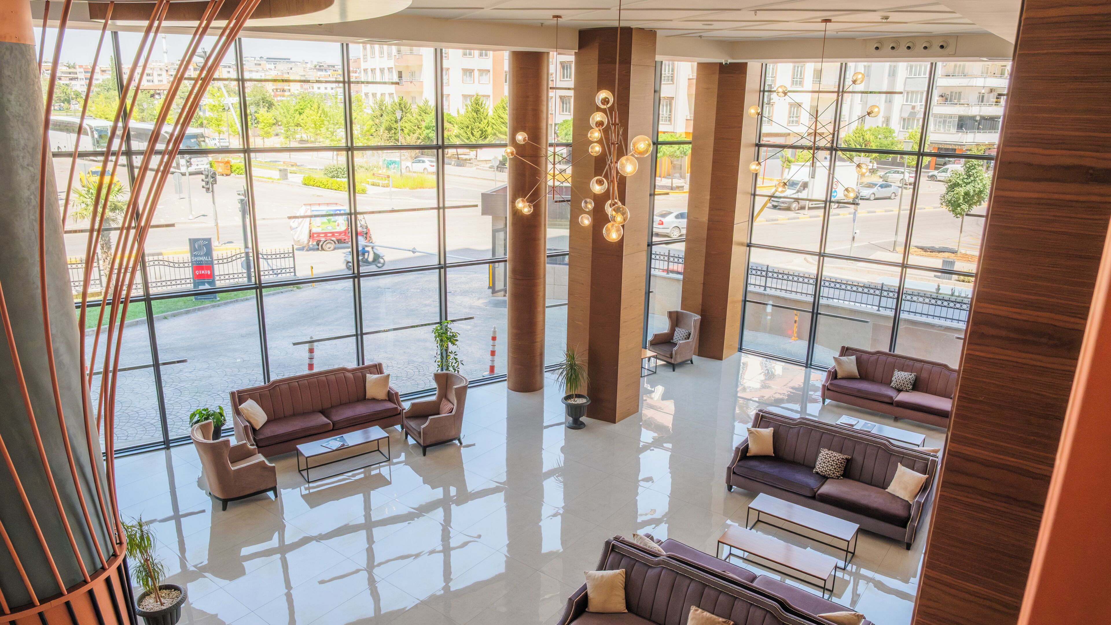Een ruime lobby met hoge plafonds, grote ramen en modern meubilair.