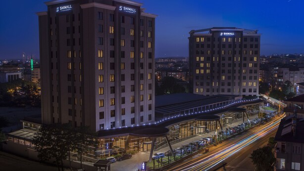 A hotel with a prominent sign, multiple floors, and a covered walkway. - Shimall Deluxe Hotel (Gaziantep)