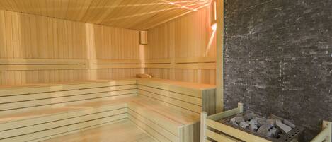 A sauna with wooden benches and a brick wall.