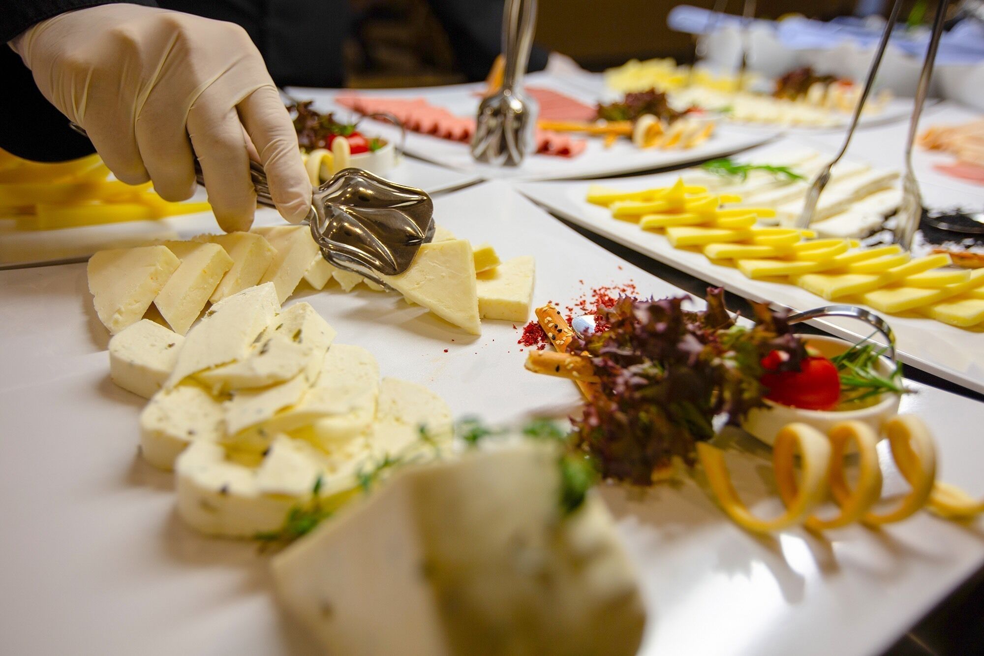 A buffet table with various food items including cheese, fries, and salad.