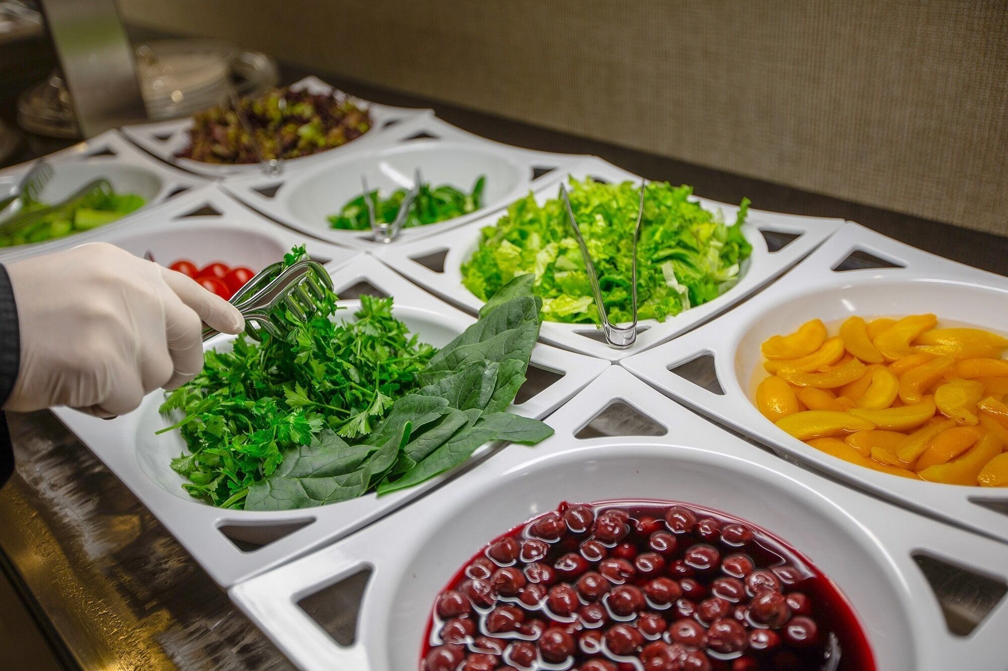 Un buffet proposant une variété de plats, notamment des légumes verts, des fruits et un saladier de cerises.