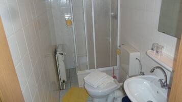 Un baño pequeño con inodoro, lavamanos y ducha.