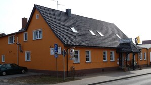 Un bâtiment avec un toit recouvert de tuiles, un panneau indiquant un espace de stationnement et un panneau indiquant un restaurant.