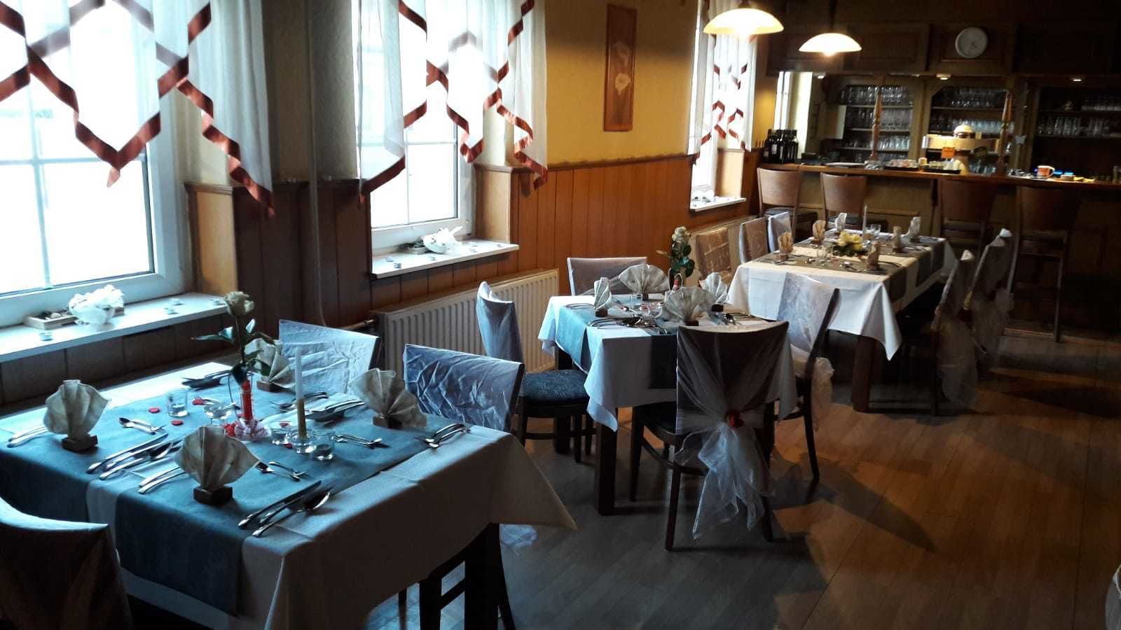 Un restaurante con varias mesas dispuestas para comer, que presenta un interior clásico con suelos y decoración de madera.