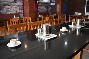 A restaurant with a black counter, white cups, and stainless steel coffee pots. - Apple Park Annexe (Tiruchirappalli)