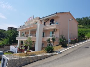 A multi-story building with balconies, a sign reading "DONI Apartments," and a landscaped garden area. - Doni Apartments (Ulcinj)
