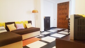 Una habitación con sofá, lámpara, refrigerador y una puerta.