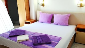 Habitación de hotel con una cama grande, dos mesitas de noche, un armario de madera y un baño a lo lejos.