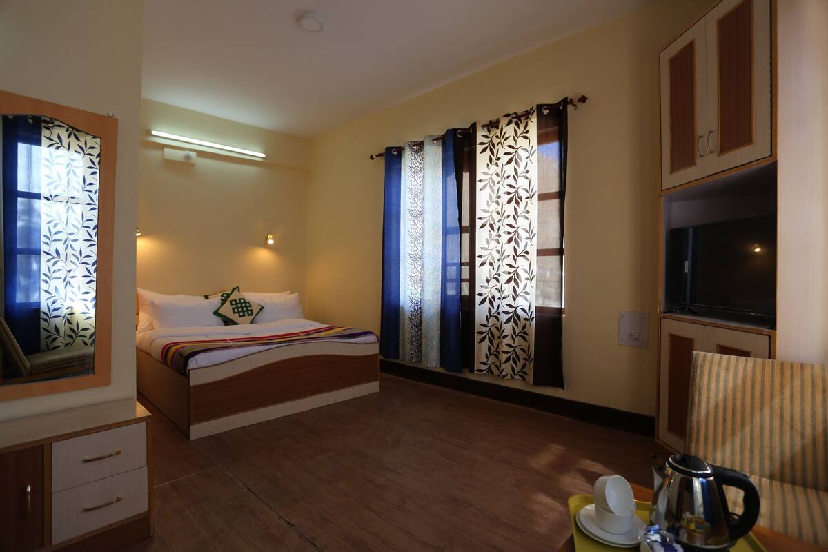 A hotel room with a bed, a chair, a desk, and a television.