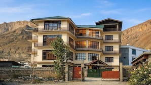 A multi-story hotel with balconies, a stone wall, and a mountainous backdrop. - Spiti Heritage (Spiti)
