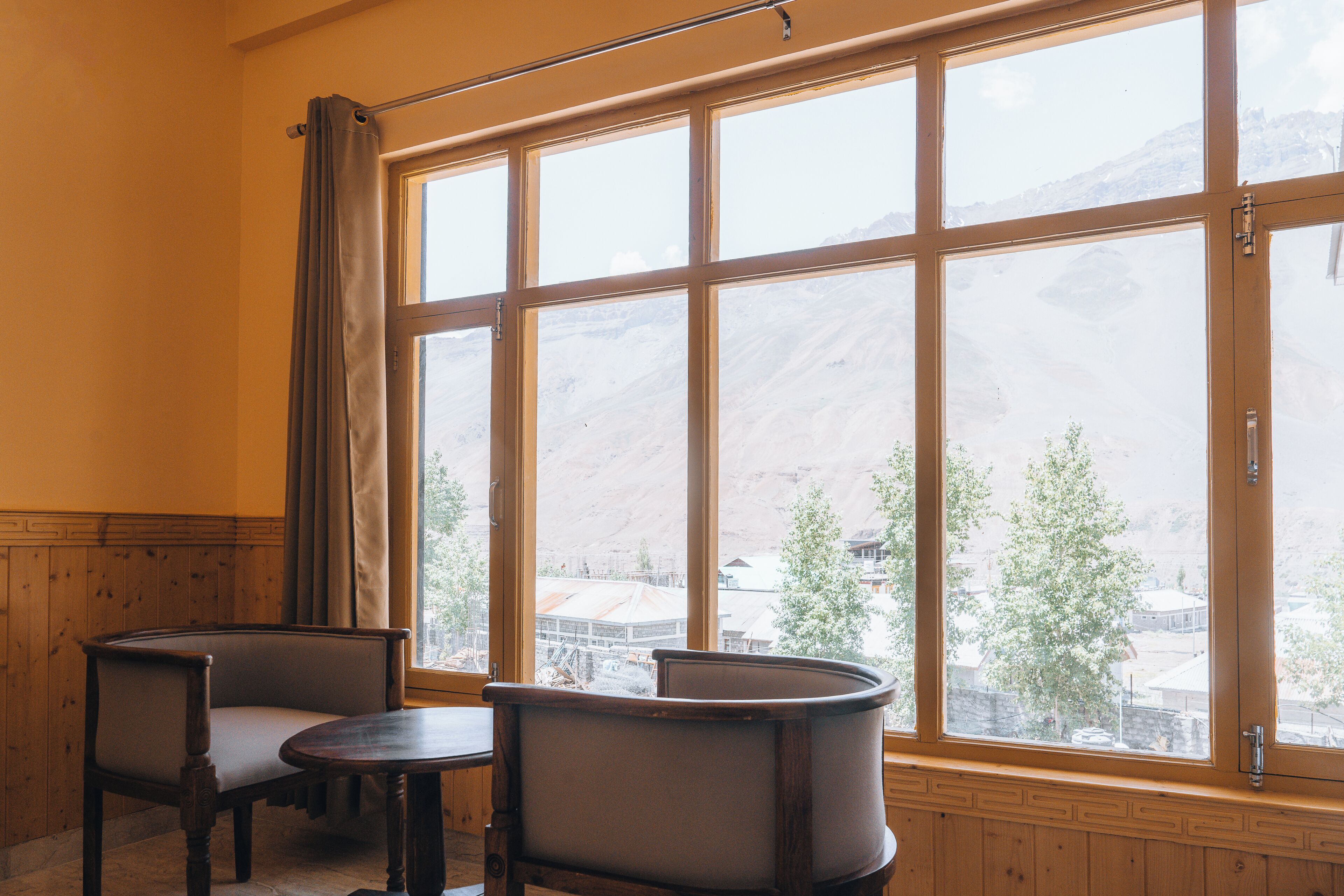 A room with a large window, two chairs, and a small table.