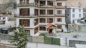 A multi-story hotel with balconies, a green roof, and a view of mountains. - Spiti Heritage (Spiti)